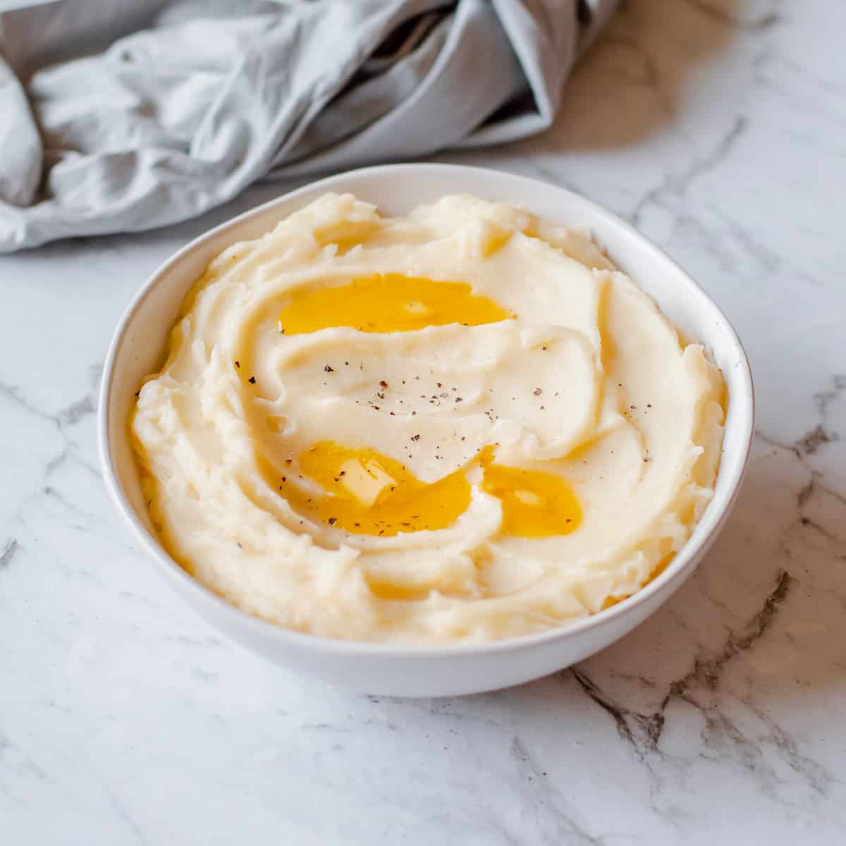 mashed potatoes in white bowl with melted butter on top