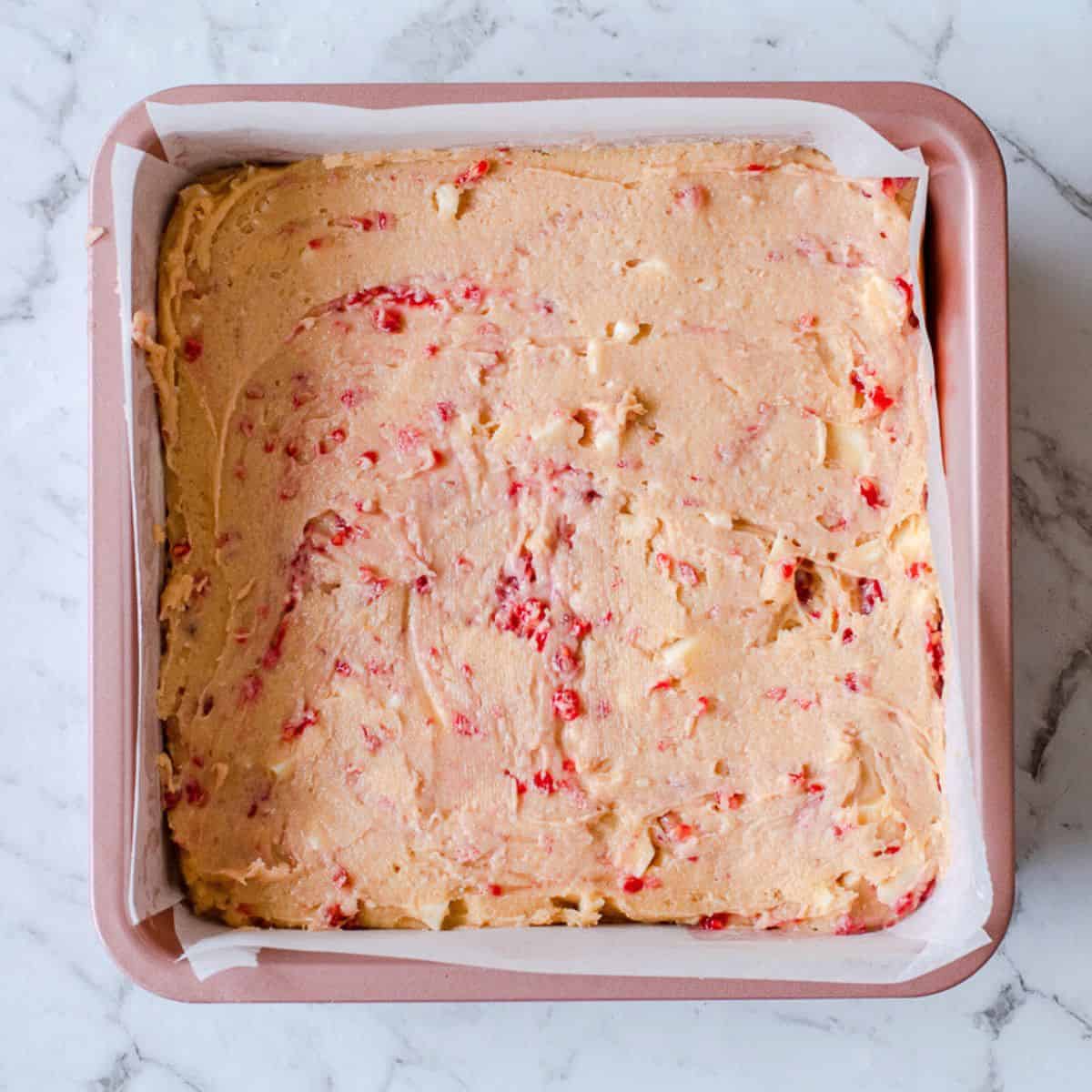 Raspberry batter in a square baking tin.