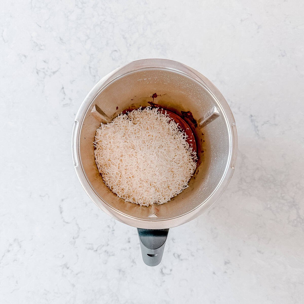 Shredded coconut and chocolate in a thermomix bowl.