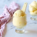 Pineapple sorbet in a clear glass sitting next to a red stripy tea towel.