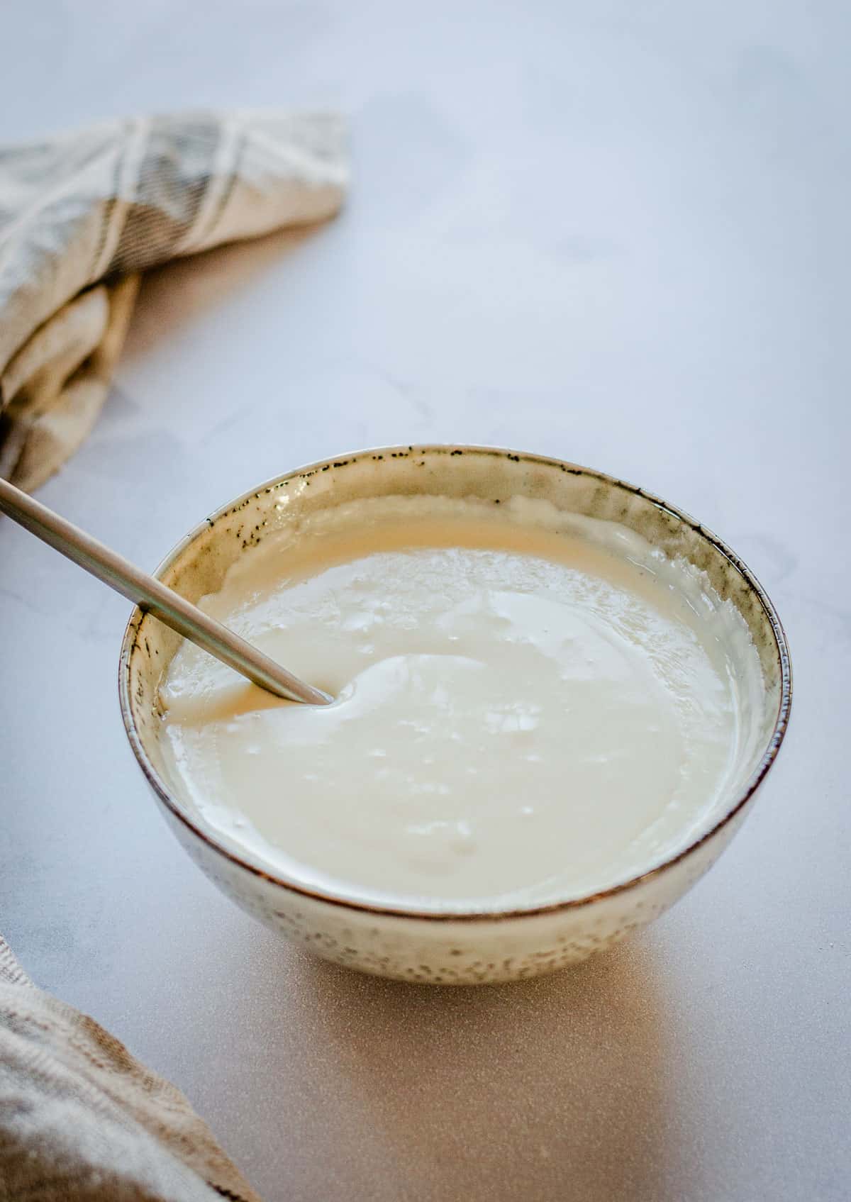 Bechamel sauce in a bowl with spoon.