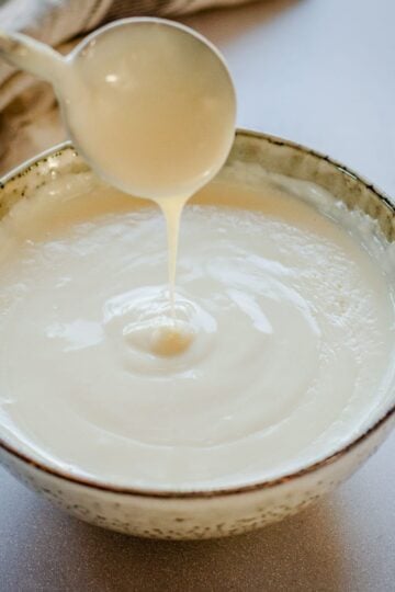Bechamel Sauce in a bowl with spoon.