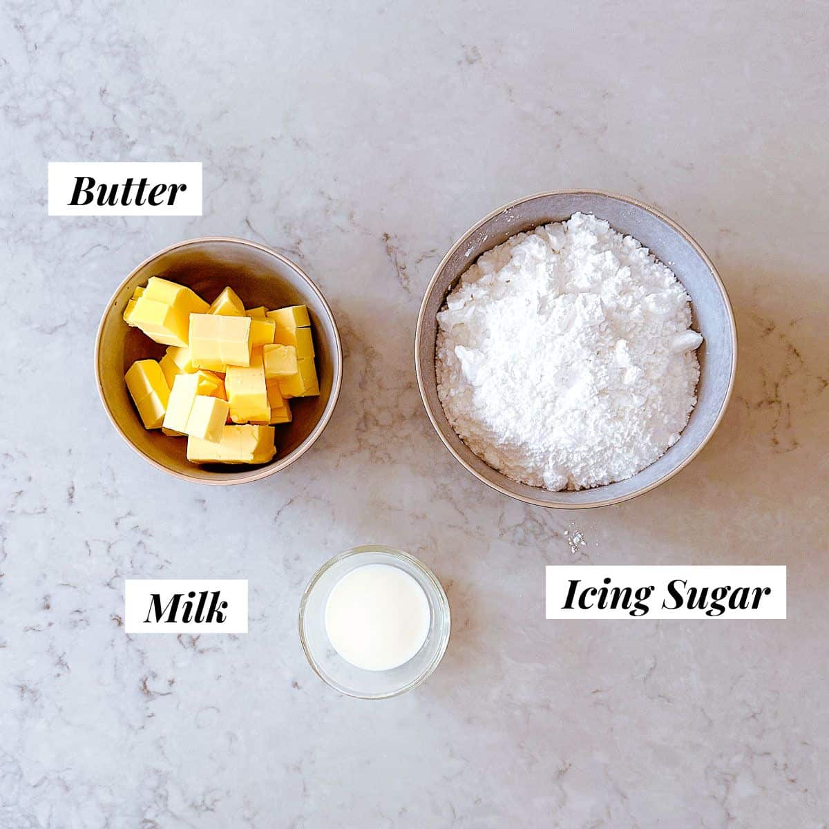 A bowl of cubed butter, milk and icing sugar - ingredients to make a buttercream icing.