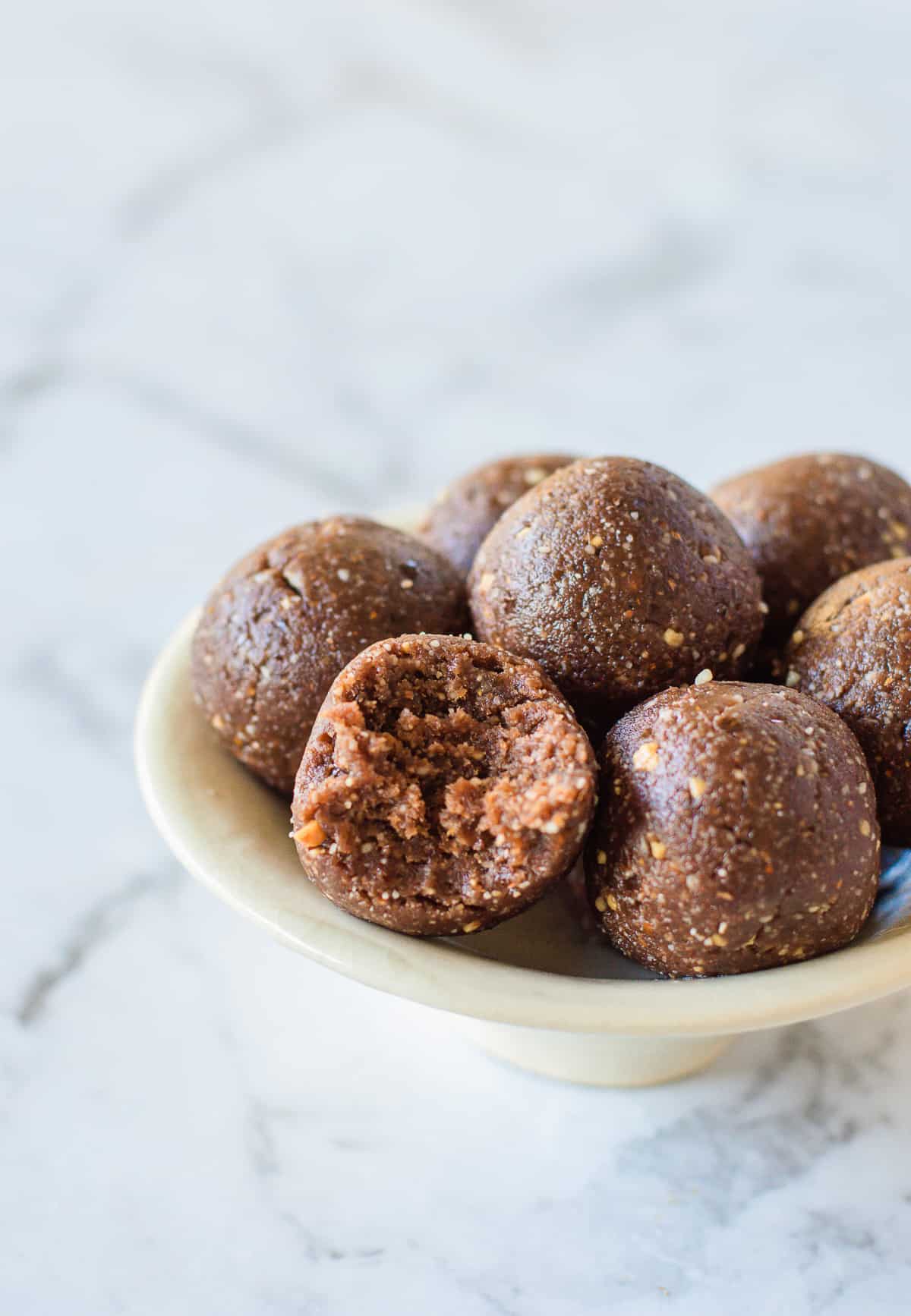 Bliss balls in a white bowl on a marble background.