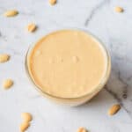 Homemade peanut butter with a few peanuts scattered around it.