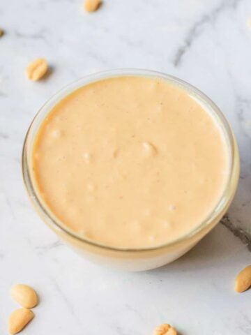 Homemade peanut butter with a few peanuts scattered around it.
