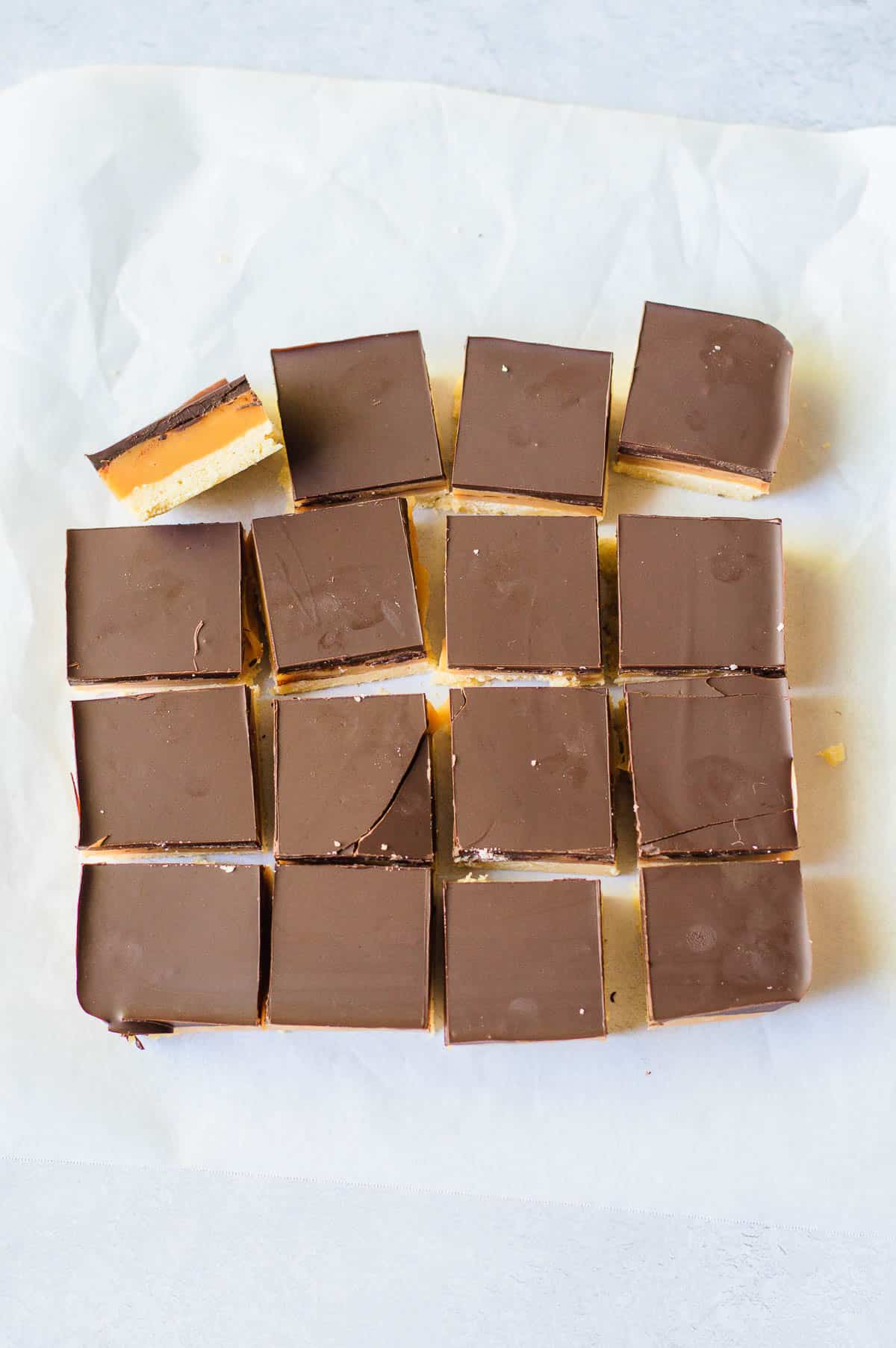 16 squares of caramel slice on a white background