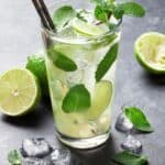 A mojito cocktail in a clear glass with mint, ice cubes and lime.