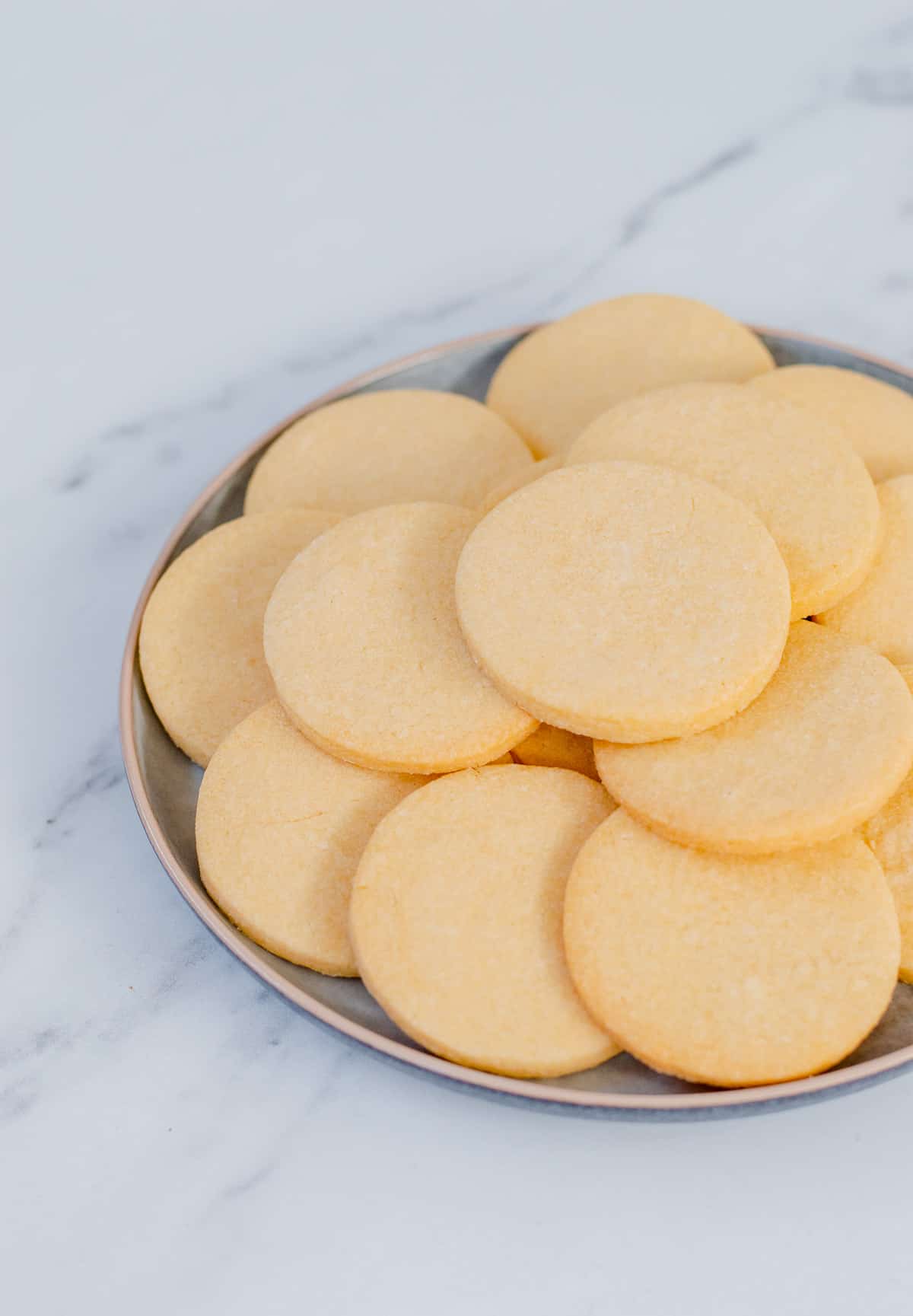 A plate of homemade sugar cookies on white marble.