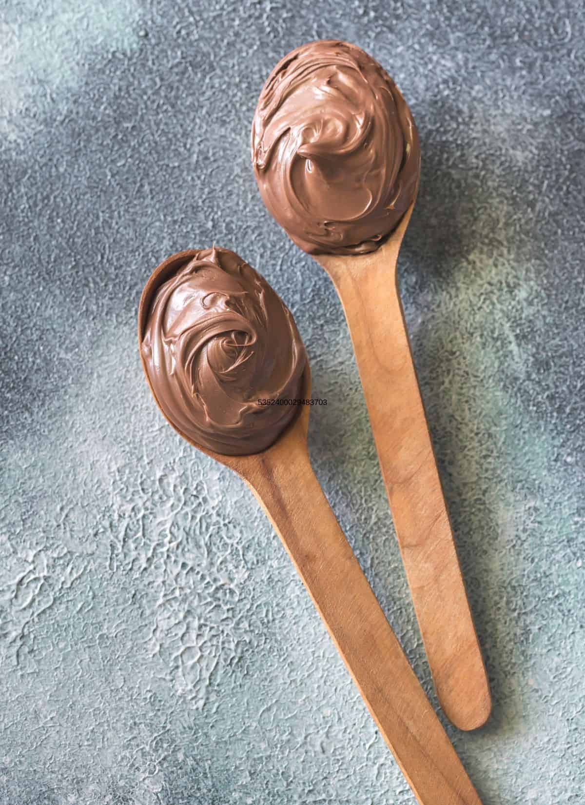 Homemade chocolate buttercreamon 2 wooden spoons.