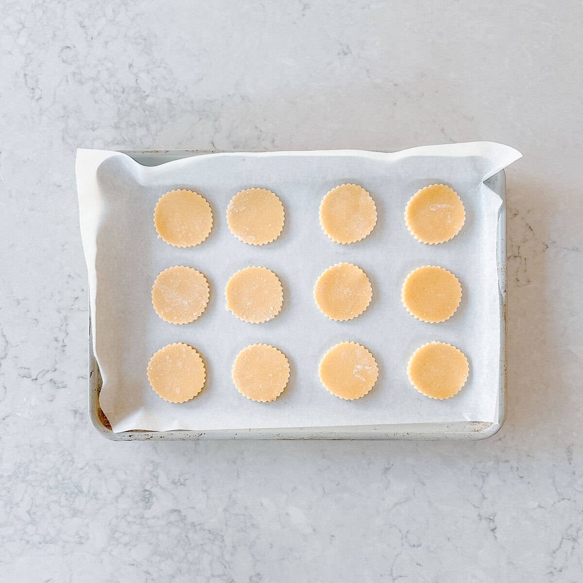 Raw cookie dough biscuits waiting to be baked on a baking tray.