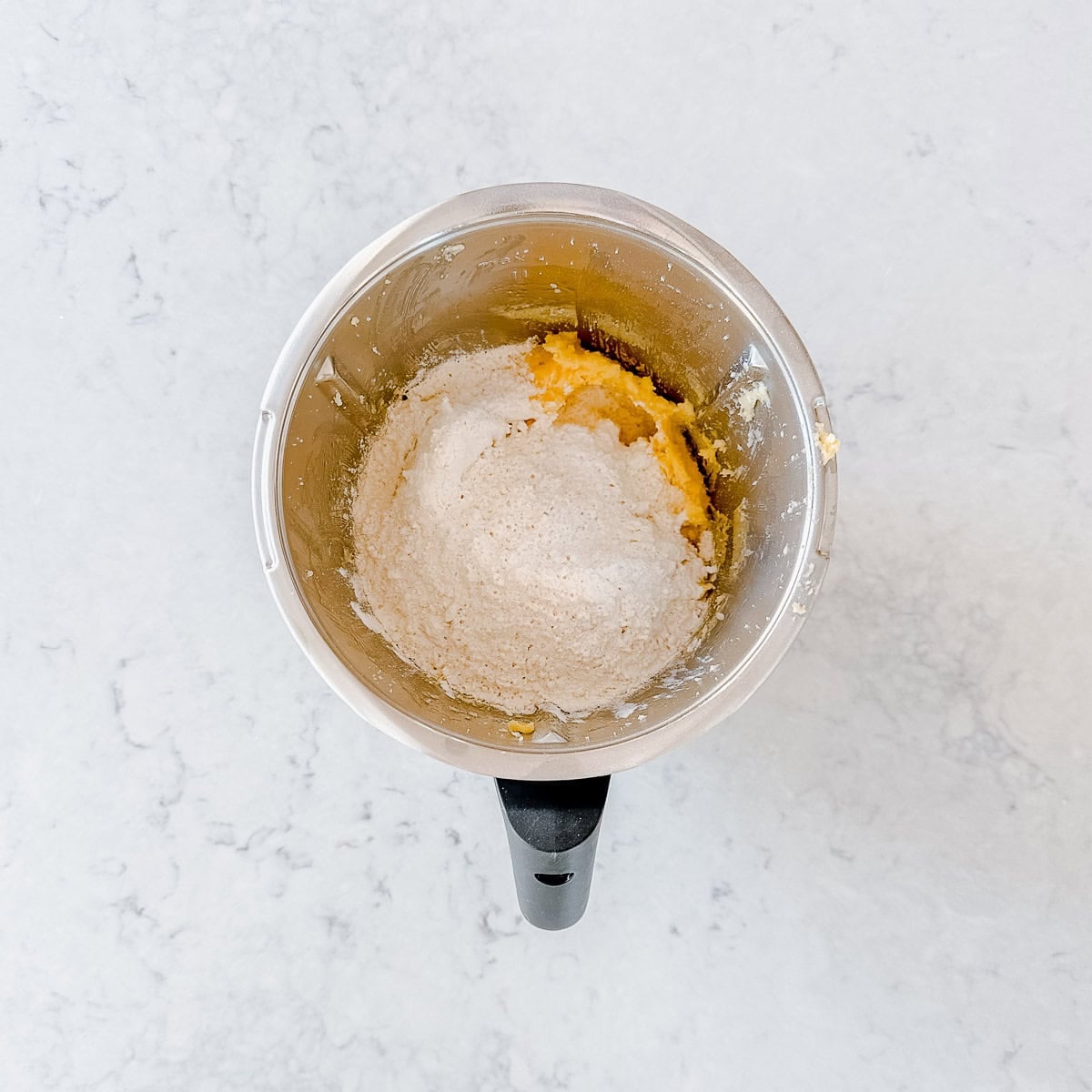 Flour added to cookie dough batter in a Thermomix bowl.