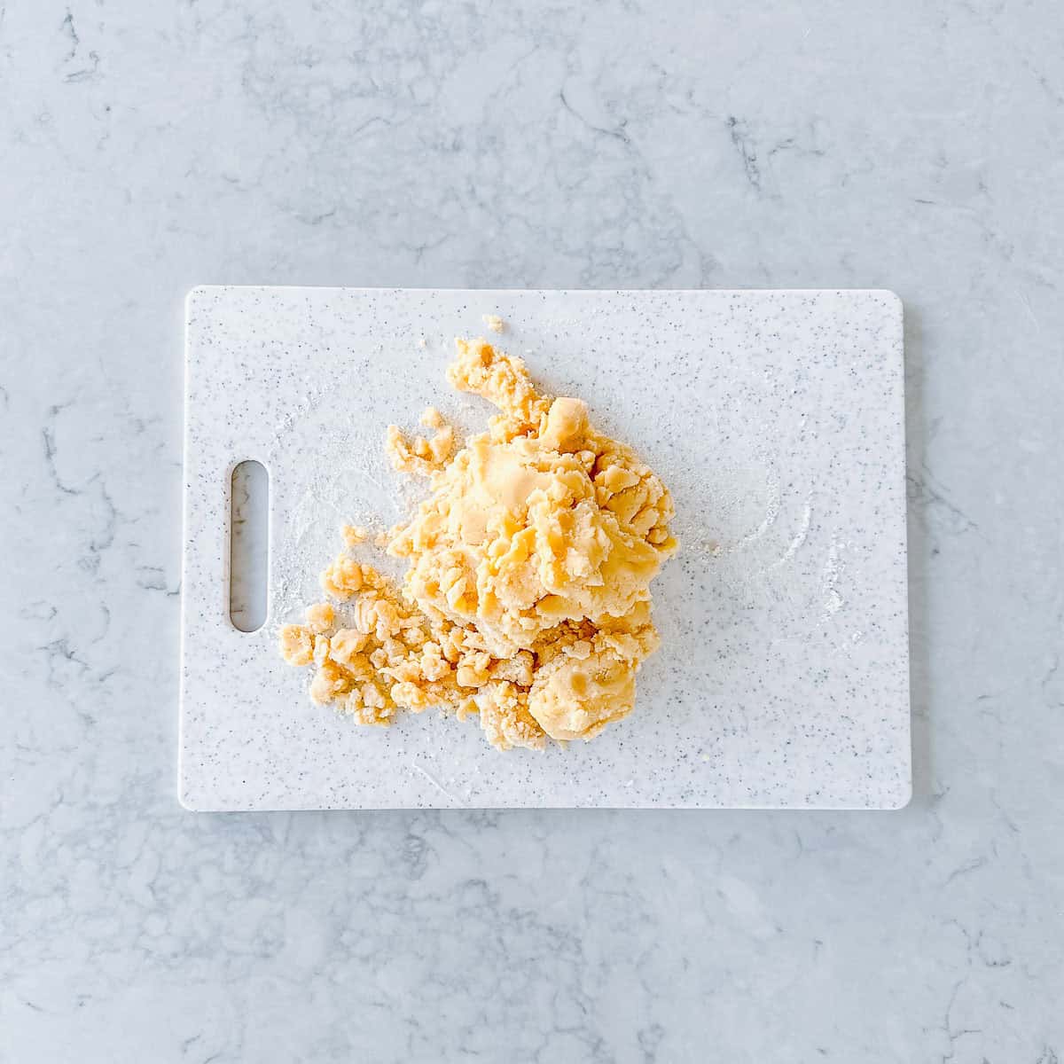 Crumbly cookie dough on a board.