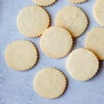 Overhead image of round cut out sugar cookies on a grey background.