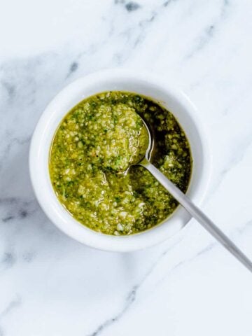 Homemade Basil Pesto in a white dish on marble background.