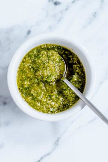 Homemade Basil Pesto in a white dish on marble background.