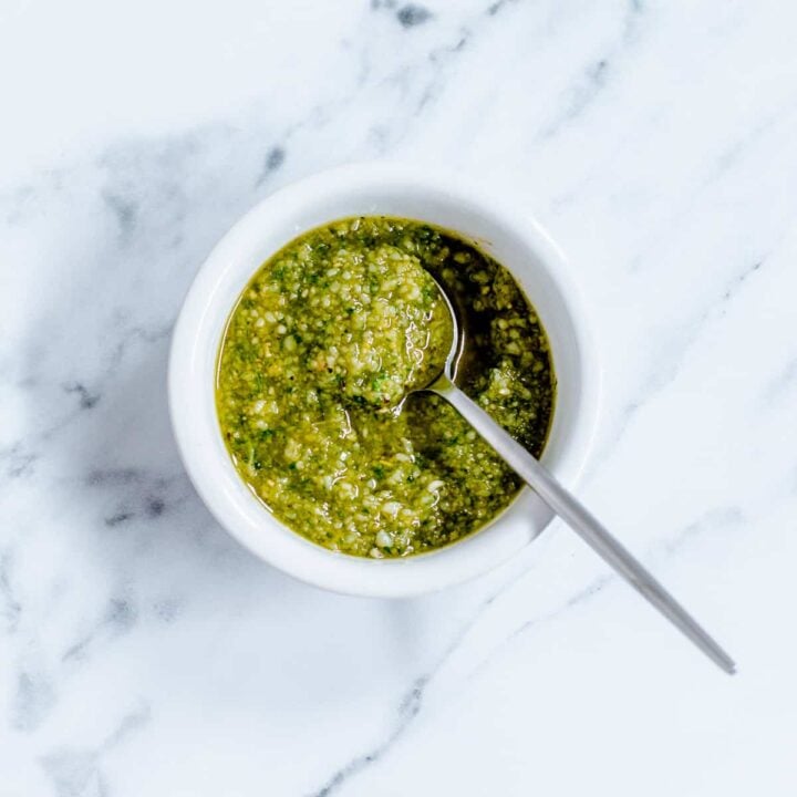 Homemade Basil Pesto in a white dish on marble background.
