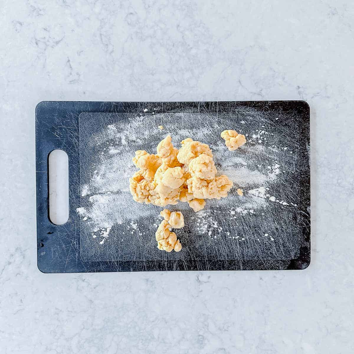 Shortcrust pastry clumps on a lightly floured surface.