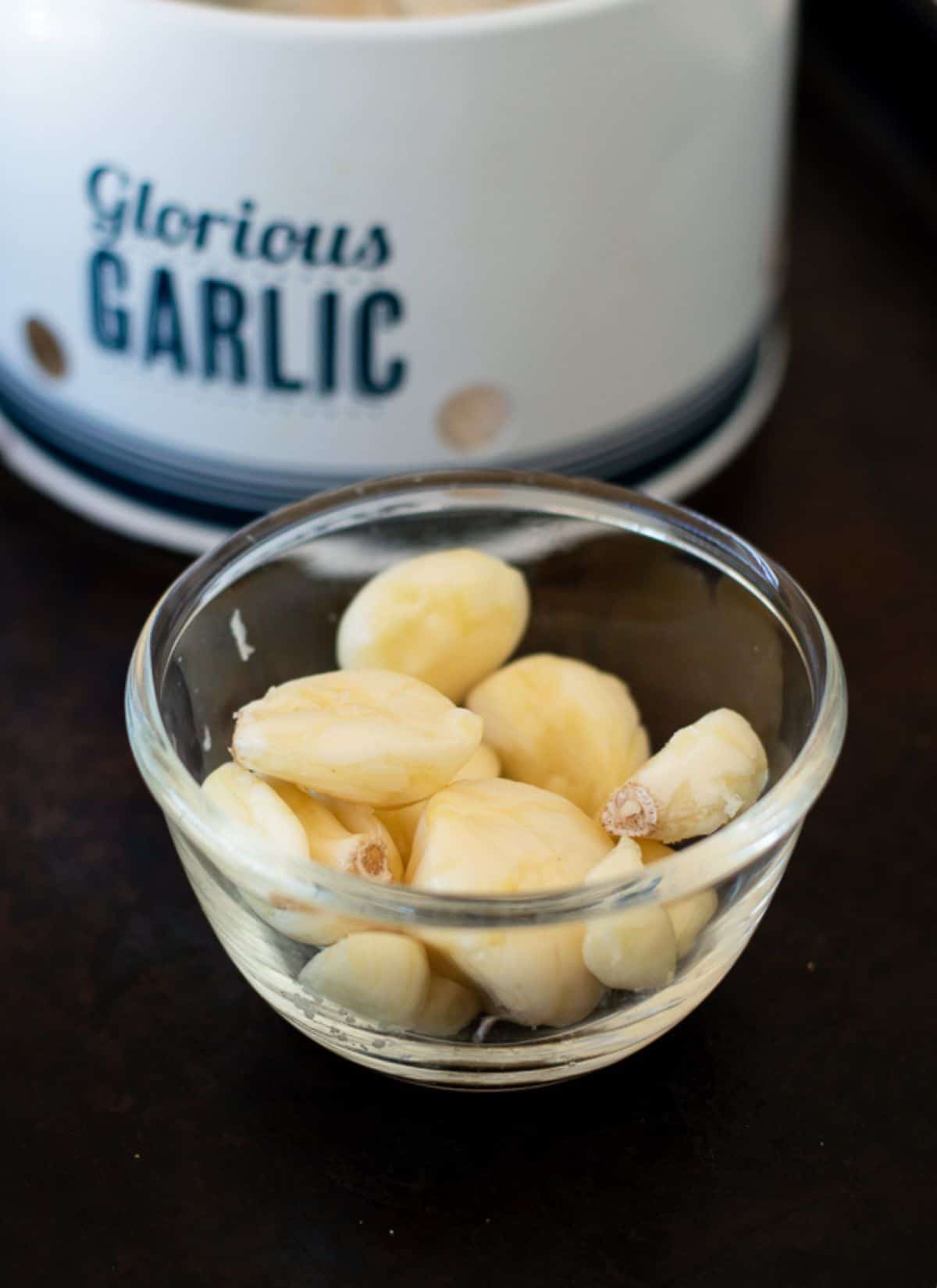 Raw garlic which has been peeled in a glass bowl.