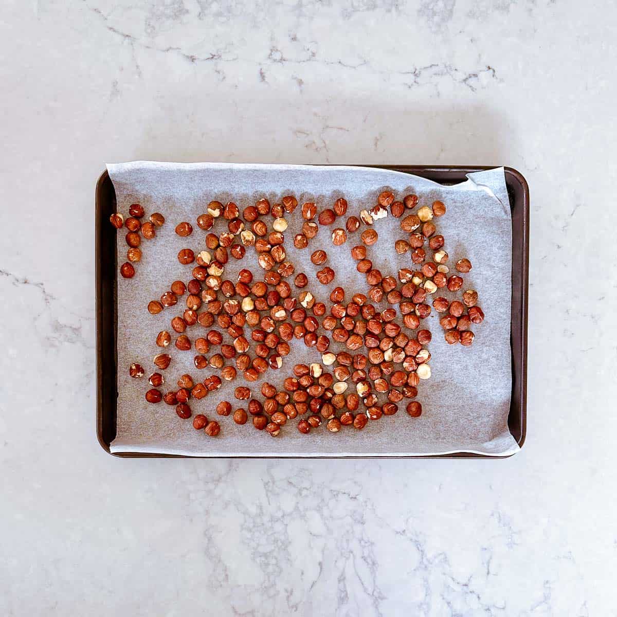 Raw hazelnuts on a baking tray.
