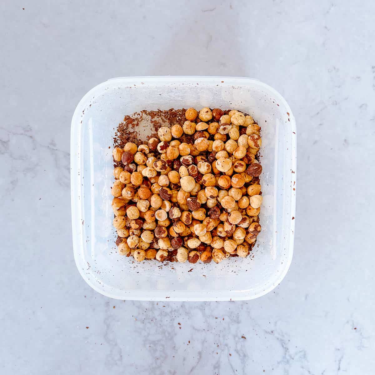 Hazelnuts in a container with their skins off.