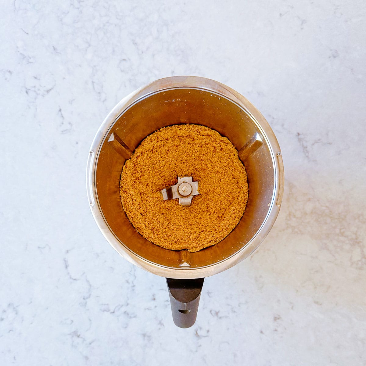 Crushed biscuits in a Thermomix bowl.