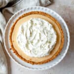 Key Lime Pie with a whipped cream topping on a white dish.