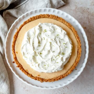 Key Lime Pie with a whipped cream topping on a white dish.