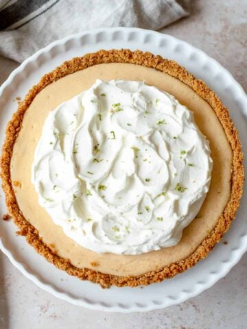 Key Lime Pie with a whipped cream topping on a white dish.