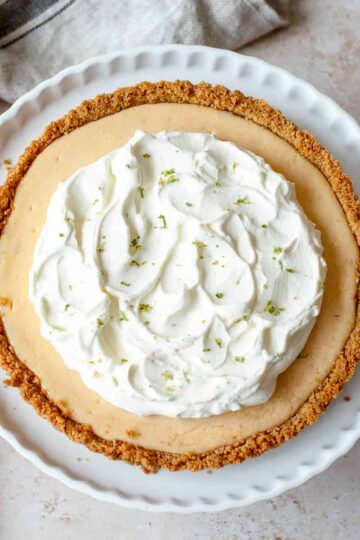Key Lime Pie with a whipped cream topping on a white dish.