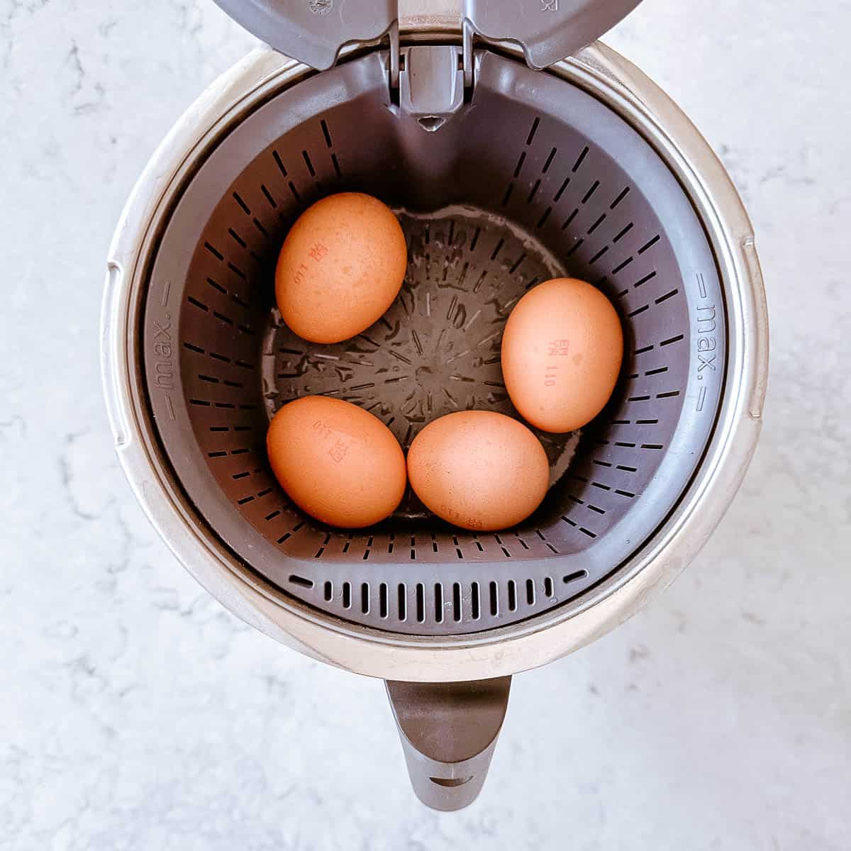 Boiled eggs sitting in a steamer basket in the Thermomix.