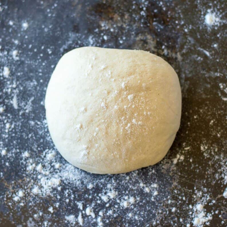 Pizza dough on a dark grey background.