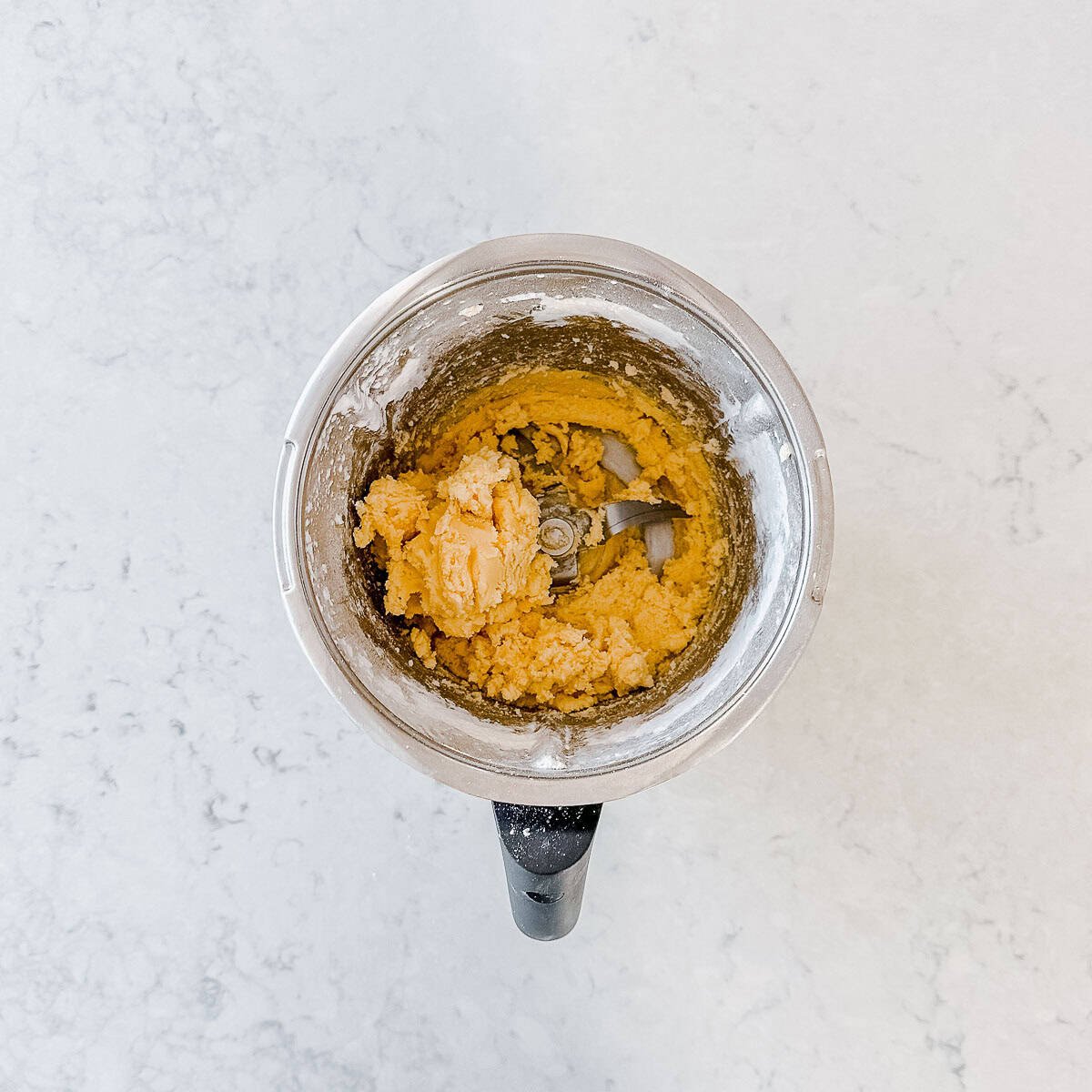 An overhead image of a Thermomix bowl filled with Melting Moments Dough.