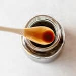 A spoonful of teriyaki sauce held over an open glass jar.