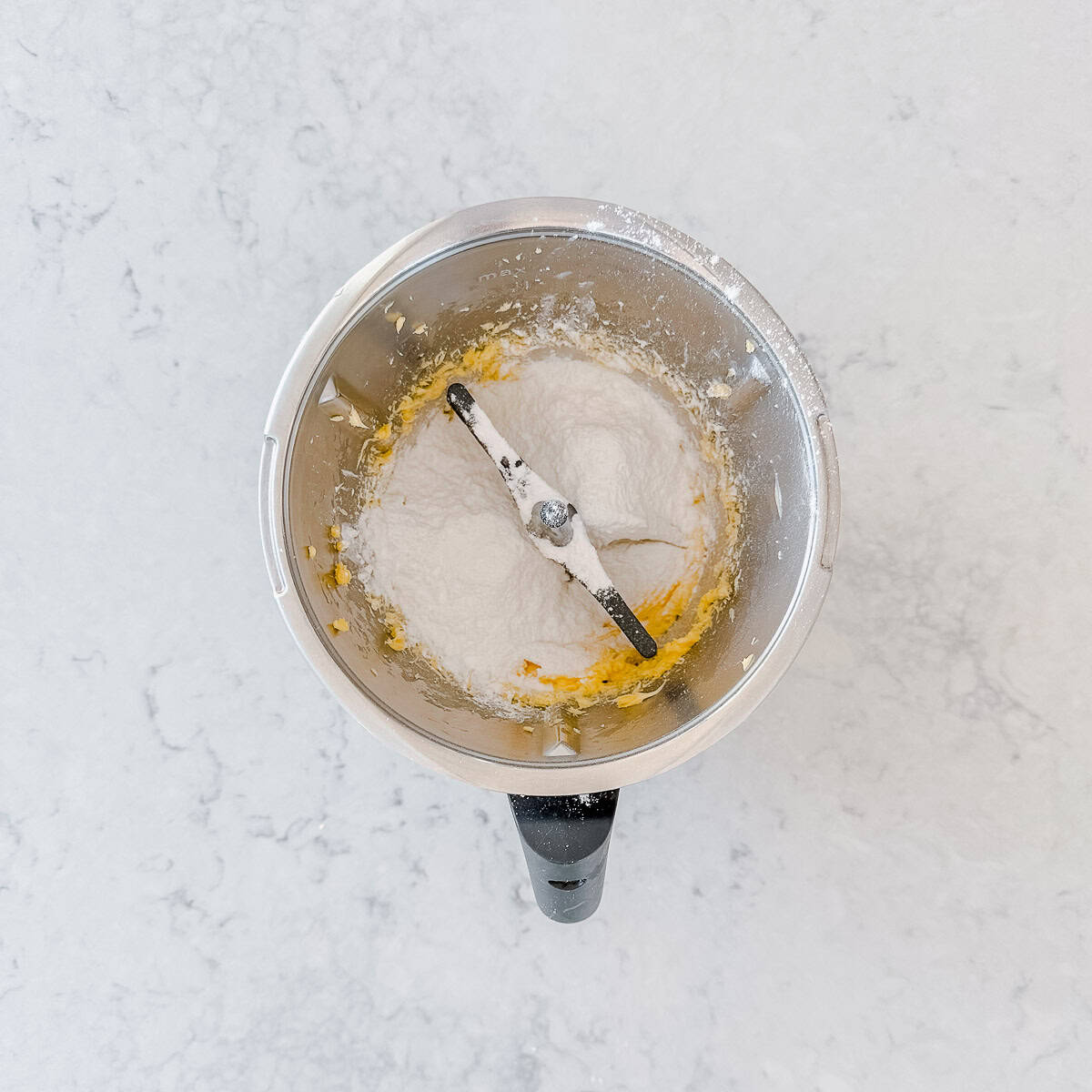 Icing sugar piled on top of the softened butter, with the butterfly whisk in place.