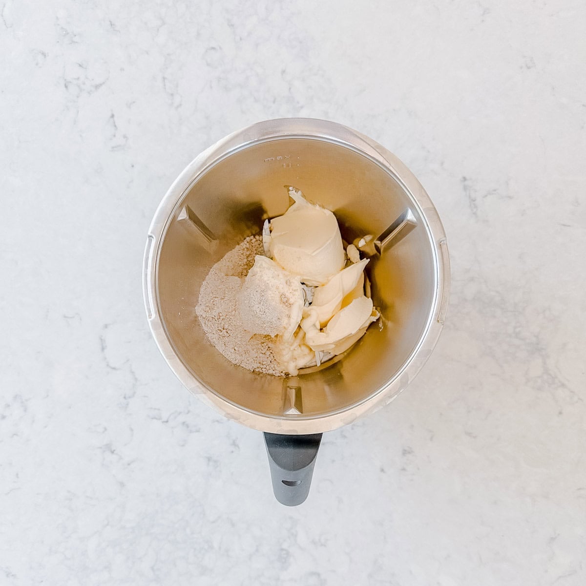 A stainless steel blender jug containing scoops of sour cream, mayo, cream cheese and some soup mix.
